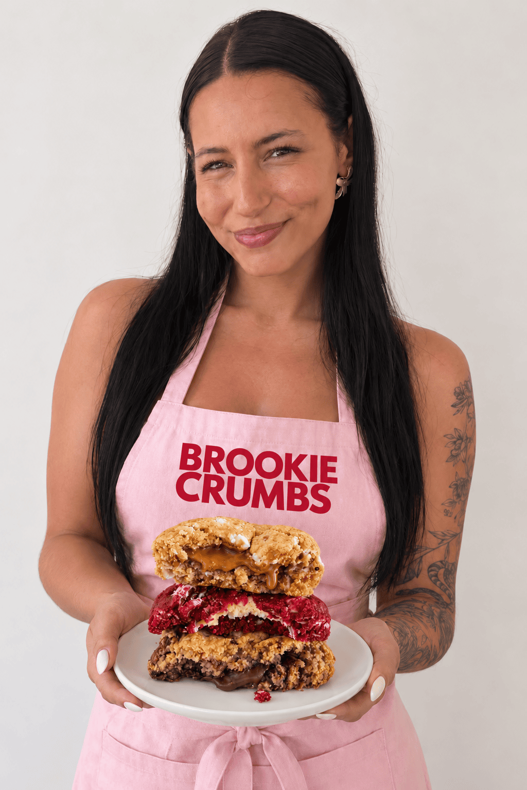 Micaela, founder of Brookie Crumbs, holding a stack of gourmet cookies